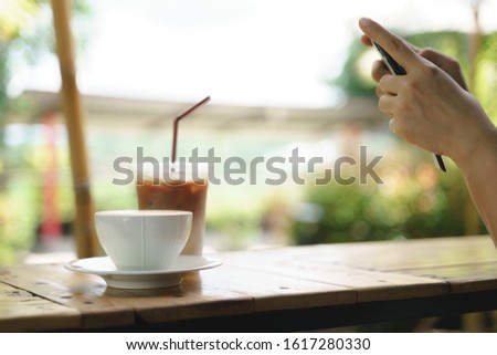 Asian woman shooting picture or take a photo of hot latte coffee with smartphone before drink