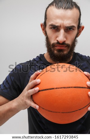 Image of young strong man in sportswear doing exercise with basketball isolated over white background