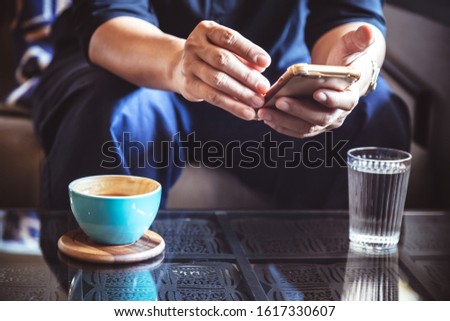 businessman using smartphone to read investment news and reply email to confirm meeting in coffee shop. man drinking latte coffee before going to work on monday morning. vintage photo and film style
