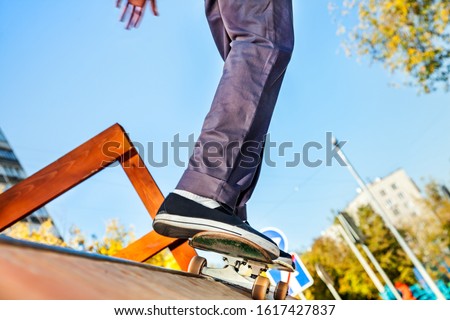 Skateboarder legs before jumping in the halfpipe in skatepark closeup