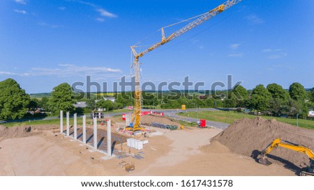 Drone photos of a large construction site on which a factory building is being erected. The foundations for the piers have been laid and and the first piers have been erected