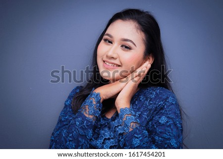 Closeup of a beautiful female Muslim model wearing dark blue modern kurung, a modern urban lifestyle apparel for Muslim women isolated on grey background. Beauty and fashion concept.