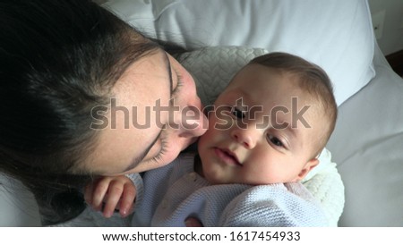 Mother kissing snugging baby infant boy at home
