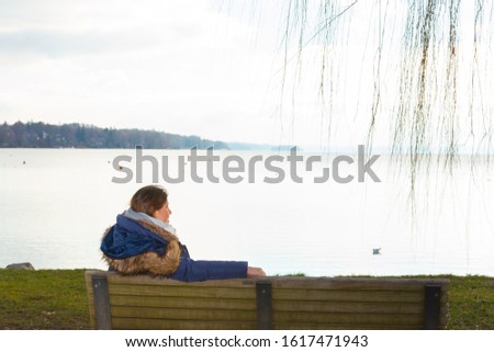 Lady sit on a bench at the lake shore admiring the beautiful landscape view.