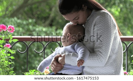 
Mom kissing baby next to window overlooking view