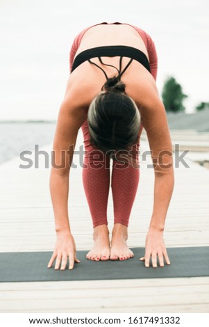 Asian young girl doing yoga outdoors on the pier by the lake.