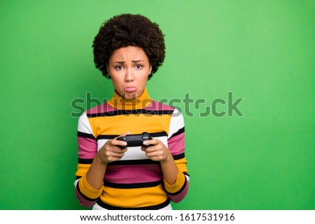 Photo of bad mood dark skin wavy lady playing video games joystick hands loser awful player crying sorrow wear casual striped sweater isolated green color background