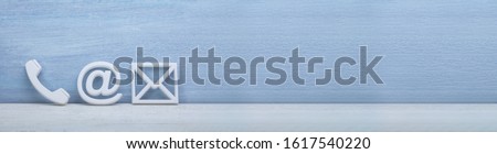 White Popular Contact Web Icons On Desk Over The Reflective Desk Against Gray Wall