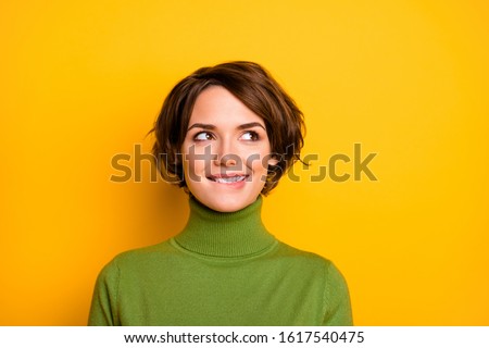 Closeup photo of funny pretty lady charming smiling good mood looking side empty space biting lips wear casual green warm turtleneck isolated yellow color background