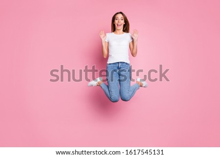 Photo of beautiful crazy lady jumping high enjoy summer sunny weekend days playful mood wear casual white t-shirt jeans sneakers isolated pink color background