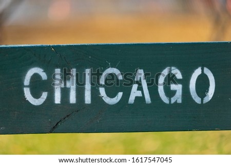 Close on an old green wood sign with painted block letters that read, "CHICAGO".