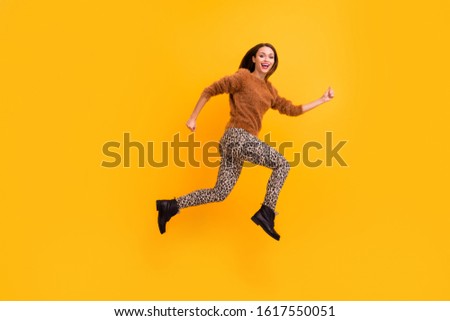 Full body profile photo of pretty funky lady jump high speed rushing shopping low prices season wear casual fluffy pullover leopard trousers footwear isolated yellow color background