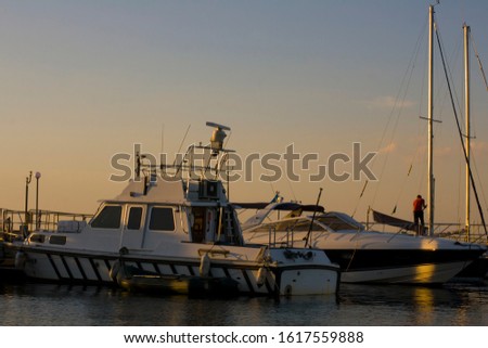 Evening in a quiet bay. Moored yachts in the port. Windless sunset in the bay. Man cleans the deck