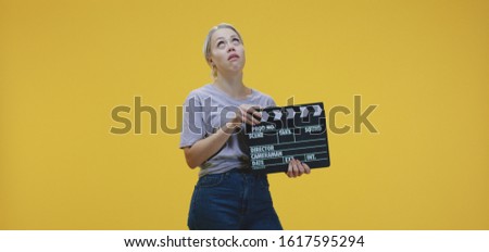 Medium shot of a bored young woman holding and clapping clapperboard