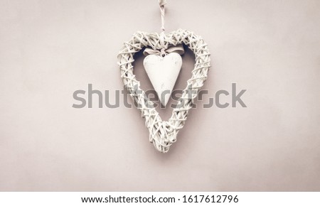 Valentine's card background - A white wooden heart surrounded by a wicker wreath on a pastel background. The perfect decoration for Happy Valentine's Day or for a wedding. A nice gift for lovers.