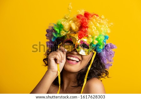 Beautiful woman dressed for carnival night. Smiling woman ready to enjoy the carnival with a colorful wig and mask Royalty-Free Stock Photo #1617628303