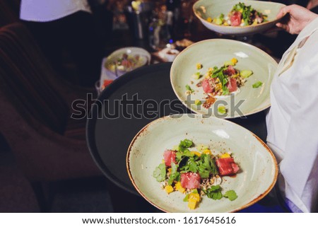 Waiter carrying a plate with fish and salad on a wedding.