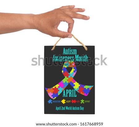 Hand holding April Autism Awareness Month (Understand, Accept, Love, Support) blackboard sign  white background
