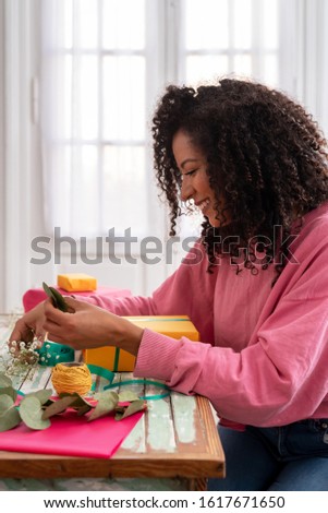 Latin woman wrapping handmade craft gifts on the table at home