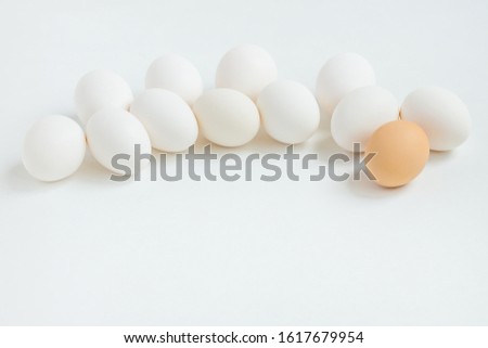 Group of white eggs on white background. Getting ready for the Easter holiday. One leader among all.