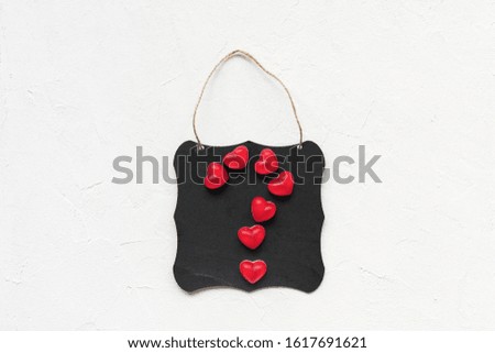 Question mark made of jelly hearts on a black board, white background, copy space. Top view, flat lay. Valentines Day concept