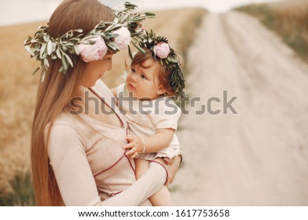 Family in a summer field. Mother in a wbrown dress. Cute little girl in a wreath