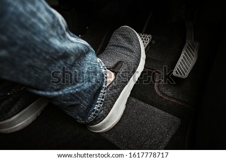 Close up the foot pressing brake pedal of a car. Driver stopping the car. Royalty-Free Stock Photo #1617778717