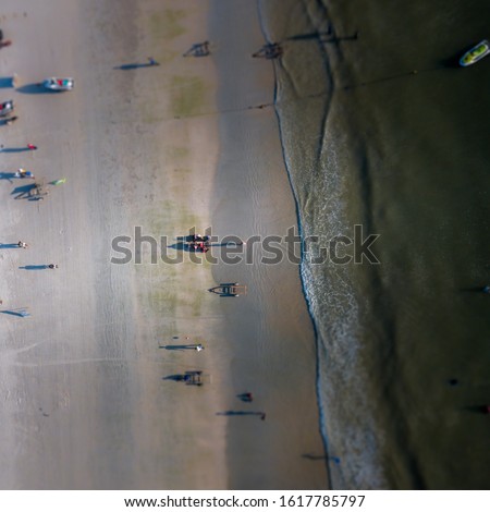 Aerial Tilt Shift View - People Walking at the beach. High angle view, camera looking down.