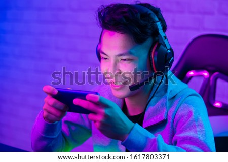 Young Asian Handsome vlogger having live stream and play online Video Game Royalty-Free Stock Photo #1617803371