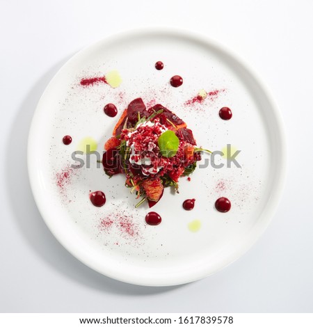Baked beet salad with citrus fruits and stracciatella on restaurant plate isolated. Red salat with sliced beets, grapefruit, pomegranate, cheese ice cream topview