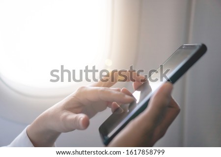 Woman hand use smartphone in airplane in offline mode during flight work and travel concept.