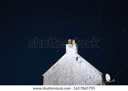 House at night with stars overhead illuminating the night sky.