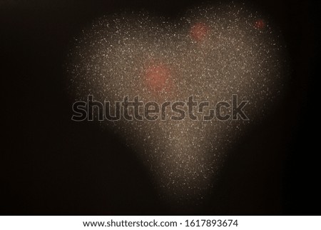 silver glitter bokeh in the form of a heart on a dark background