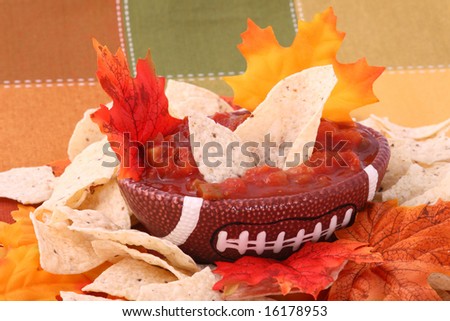 football shaped bowl with chips, salsa and fall colored leaves
