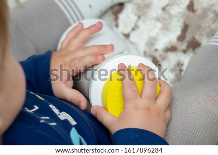 A child independently tries to open a plastic bottle of medicine, close-up. Child-resistant, childproof or CR packaging. Push&Turn Cap. Child safety concept Royalty-Free Stock Photo #1617896284