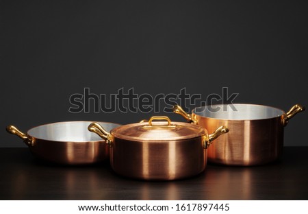 Shiny vintage copper cookware over dark background Royalty-Free Stock Photo #1617897445