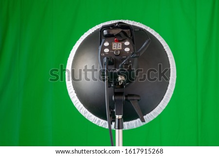 Backside view of a flash light with a beauty dish and a connected remote trigger on a tripod