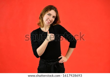 A universal concept, the picture is suitable for any topic. Studio portrait of a pretty blonde girl in a black T-shirt on a red background with bright emotions.