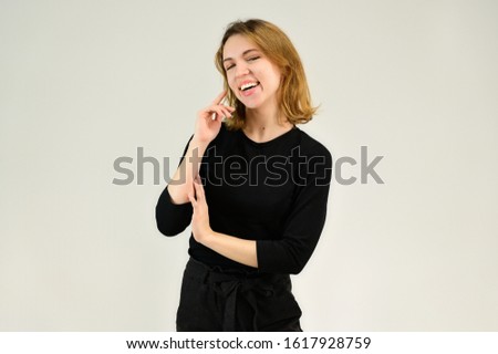 Studio portrait of a pretty blonde girl in a black T-shirt on a white background with bright emotions. A universal concept, the picture is suitable for any topic.