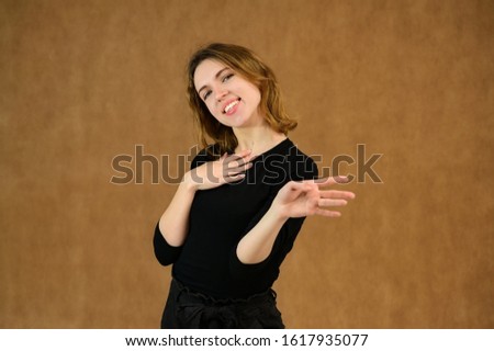 Studio portrait of a pretty blonde girl in a black T-shirt on a beige background with bright emotions. A universal concept, the picture is suitable for any topic.