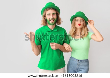Young couple on light background. St. Patrick's Day celebration