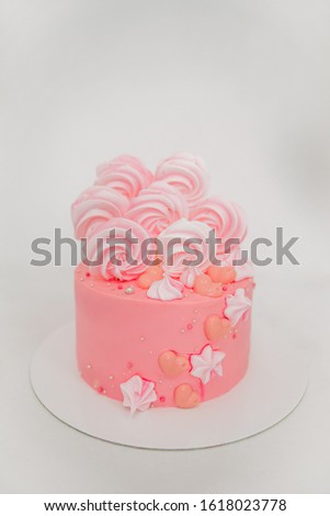 Pink cake with meringues and marshmallows on a white background