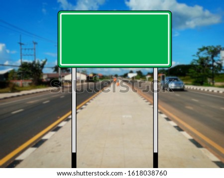 Green blank traffic sign without message The background of the road is blurred