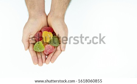 Multicolored, sweet, tasty marmalade hearts in men's hands