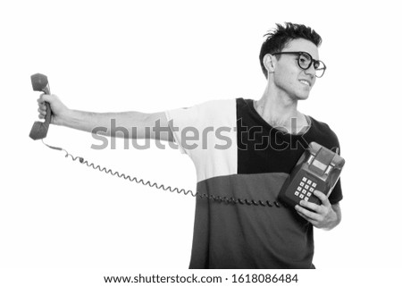 Studio shot of annoyed young man holding old telephone away
