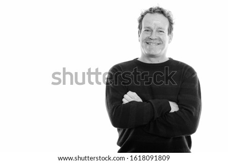 Studio shot of mature happy man smiling with curly hair and arms crossed