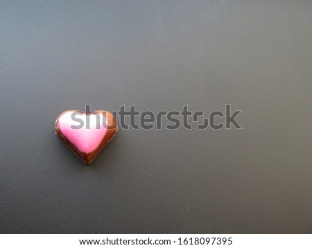 A heart shaped pink chocolate on blackbackground