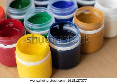 
Paint brushes and watercolor paints,  tempera paints on the table in a workshop, selective focus, close up, on wooden background. Set of gouache - bouquet