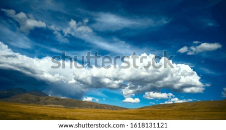 hills, lighting up an lake down in valley.Grass,rocks and mountains also featured in the picture.green field, mountains and cloudy sky sunset. Beautiful landscape, grass. mountain Altai 