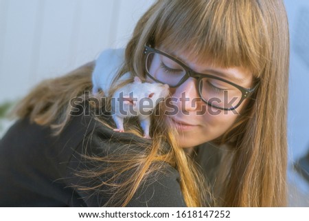 Teenage girl in glasses plays with white pet rat